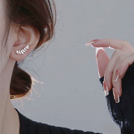 Close-up view of a woman wearing the silver leaf stud earring to showcase its scale and appearance.