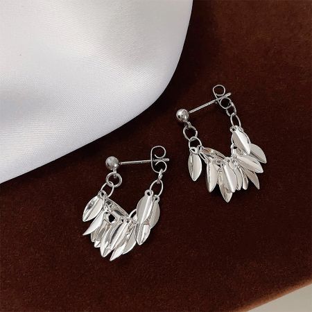 Silver leaf statement earrings elegantly displayed on a rich brown velvet surface.