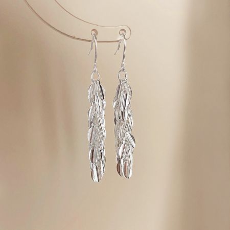 A detailed product shot of the pair of silver earrings, highlighting their feather-like design.