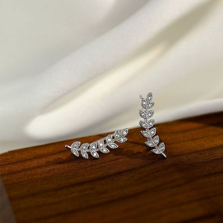 A detailed product shot of the silver leaf-shaped earrings with brilliant crystal details.