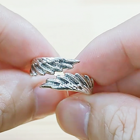 A delicate leaf-inspired sterling silver ring held between fingers to show detail.
