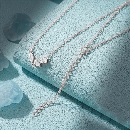 The sterling silver version of the geometric cluster necklace elegantly displayed on a light blue stand.