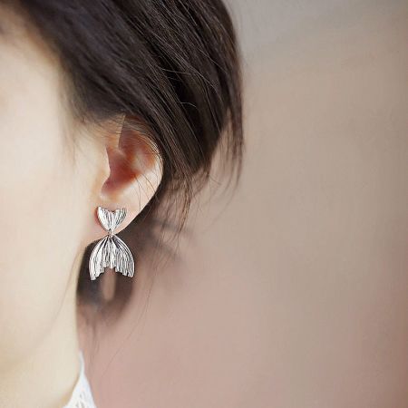 A model wearing the sterling silver mermaid tail earring to show its scale and style.