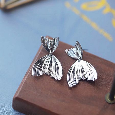 A close-up shot of the pair of silver mermaid tail earrings, highlighting the detailed craftsmanship.