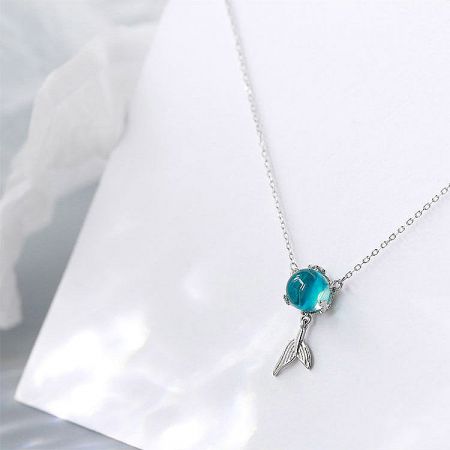 Angled view of the blue moonstone fish-tail pendant necklace.