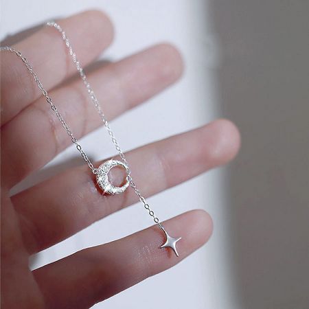 Product photo of the silver necklace featuring a crescent moon and star charm.