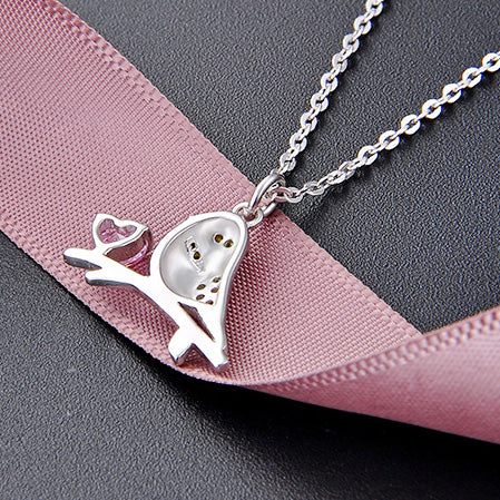 Angled view of the sterling silver bird and heart pendant, showcasing its polished finish and craftsmanship.