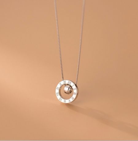 Detailed view of the silver necklace pendant, featuring a unique clock-face design with a rotating center.