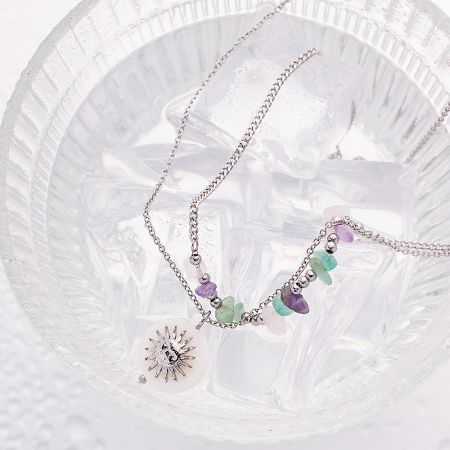 Close-up detail of the silver sun pendant necklace with multicolored stones.