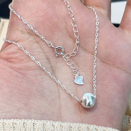 View of the necklace clasp and extension chain, featuring a small heart charm detail.