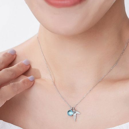 Detailed view of a silver necklace with a blue bead and elegant wing-shaped pendant.