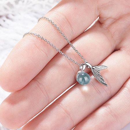 Side view of a silver necklace with a unique pendant featuring a blue-gray bead and a wing charm.