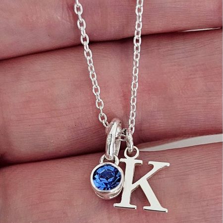 Personalized Alphabet Letter Necklace with Birthstone Accent - A close-up of the personalized alphabet letter necklace, showing a 'K' initial pendant in 14K gold-plated stainless steel with a vibrant blue birthstone accent.