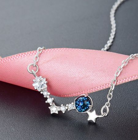 925 Sterling Silver Wishing Stars Necklace - A detailed studio shot of the 925 Sterling Silver Wishing Stars Necklace, highlighting its central blue gemstone and delicate star-shaped cubic zirconia charms on a silver chain.