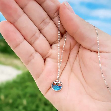 Close-up view of the sterling silver whale tail pendant, highlighting the craftsmanship and the vibrant blue gemstone.