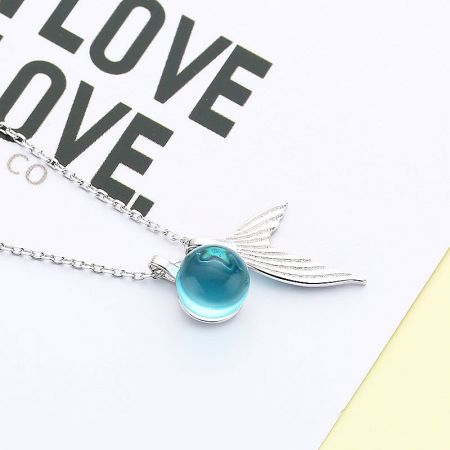 A minimalist silver necklace highlighting a striking blue pendant.