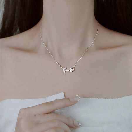 A nature-inspired silver necklace featuring a detailed branch pendant.