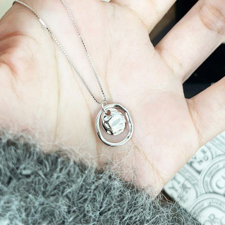 Detailed view of a sterling silver necklace with a unique circular pendant design.