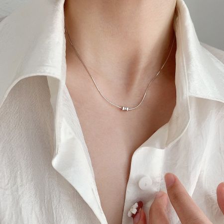 Detailed view of a sterling silver necklace from the set, with a unique double-bead pendant.