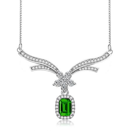 Close-up detail of the emerald pendant, showing the large green gemstone surrounded by smaller clear stones.