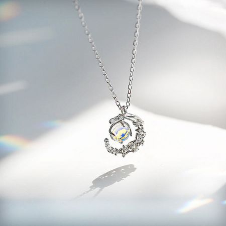 A 925 silver necklace from the set, featuring a pendant with an iridescent stone and a delicate bird in flight design.