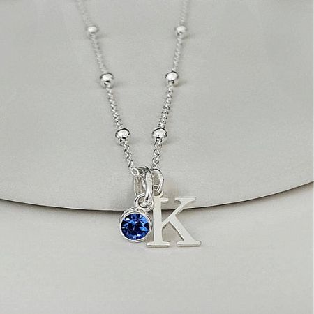 Customizable stainless steel initial 'K' pendant necklace with a brilliant blue birthstone accent.