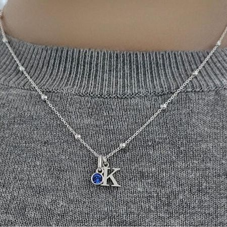Side view of the alphabet 'K' initial necklace with a blue gemstone.