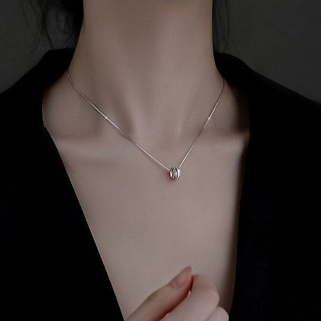 Product shot of a silver necklace from the set with a delicate oval pendant on a white background.