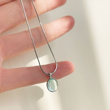 A silver necklace with an oval-shaped pendant, likely made of a light-colored stone.