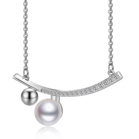 Detailed view of the pearl and cubic zirconia pendant on the elongated bar necklace.
