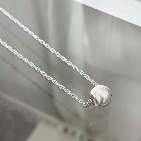 Detailed view of the 8mm spherical sterling silver pendant on the choker necklace.