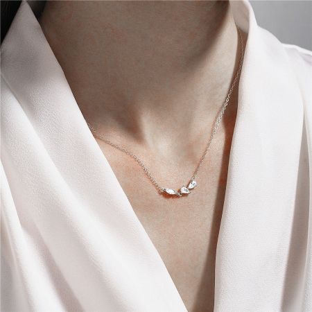 Close-up shot of the silver necklace, emphasizing the clarity and sparkle of the three clear gemstones.