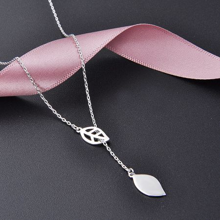 Stylishly presented silver leaf necklace against a dark background with a decorative pink ribbon.