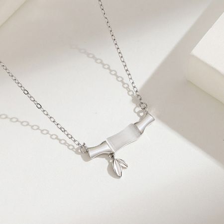 Elegant silver necklace featuring a white tube pendant accented with a small leaf charm.