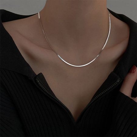 A woman wearing the silver herringbone snake chain necklace with a black top, showcasing its elegant look.
