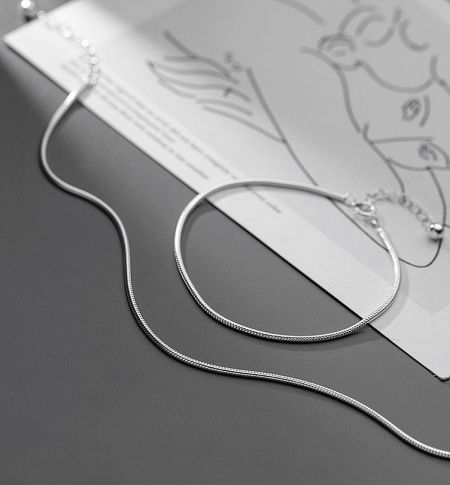 925 Sterling Silver Round Snake Chain Necklace and Bracelet Set - A pair of 925 sterling silver round snake chain necklaces displayed elegantly on a decorative tray.