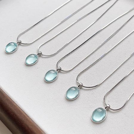 A collection of silver necklaces with pale blue gemstones arranged diagonally.