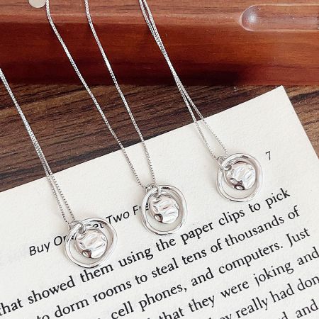 Three sterling silver necklaces with unique circular pendants displayed.