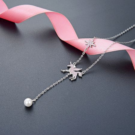 A pair of sterling silver necklaces, one with a unicorn charm and the other with a pearl, displayed side-by-side.
