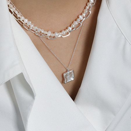 The silver square pendant necklace styled with a simple white shirt for an elegant, everyday look.