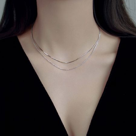 A woman wearing the 925 silver double-layer snake and link chain necklace set to showcase its fit.