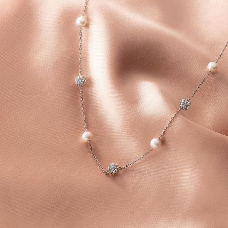 Elegant silver pearl and CZ necklace on a satin background.