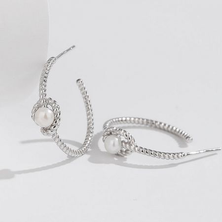 Detailed shot of the silver earrings showcasing the lustrous pearl accents.