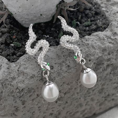 Side view of the silver snake pearl drop earrings highlighting the green gemstone eyes.