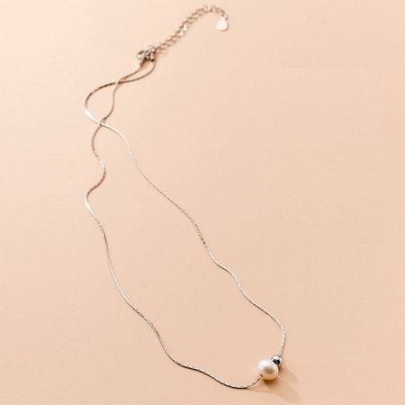 Another product view of the silver necklace with its pearl pendant against a white background.