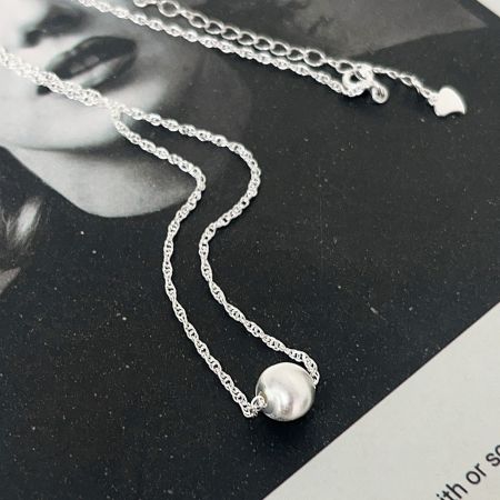 The 925 sterling silver ball charm necklace displayed on a neutral background to highlight its shine.