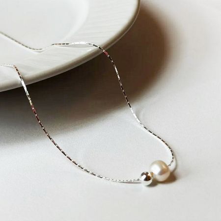 Detailed product shot of the silver pearl necklace, emphasizing its craftsmanship and design.