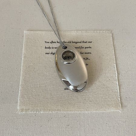 Detailed view of the silver U-shape pendant, showcasing its polished brass finish.