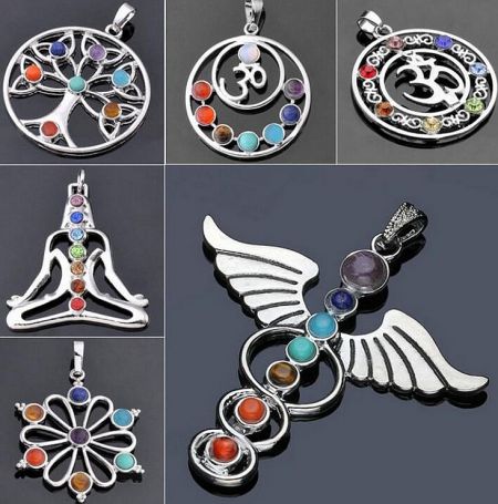 Various designs of silver chakra pendants with colorful gemstones, including tree of life and flower motifs.