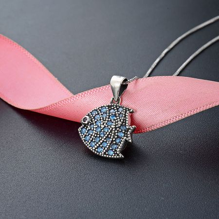A 925 sterling silver pig-shaped pendant necklace with blue gemstone accents, shown on a pink ribbon.